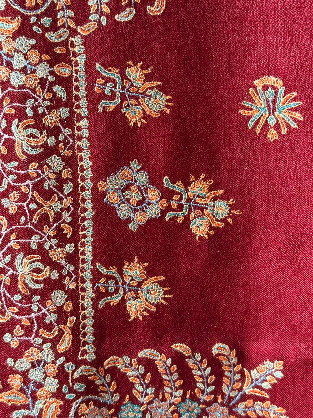 Close-up of a maroon fabric with intricate floral embroidery