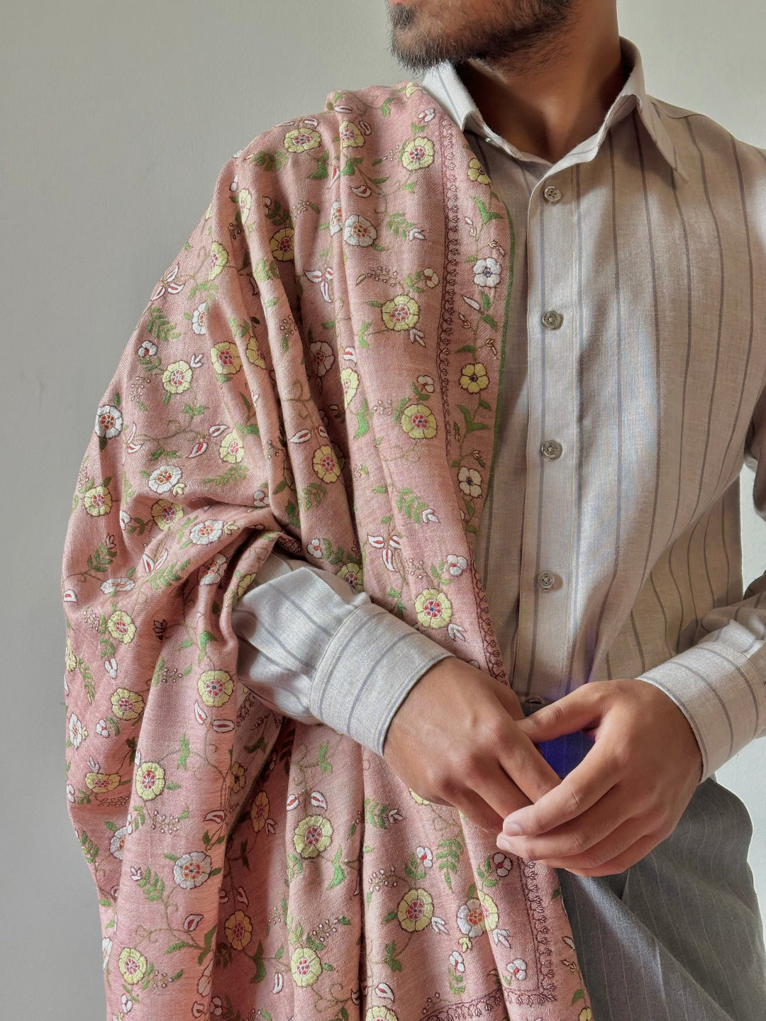 Person wearing a floral-patterned shawl over a striped shirt against a neutral background