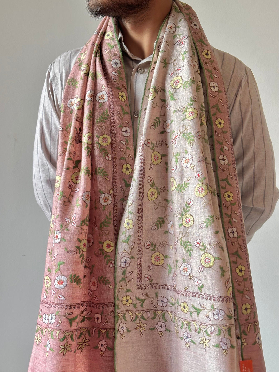 Person wearing a floral patterned scarf with a neutral background