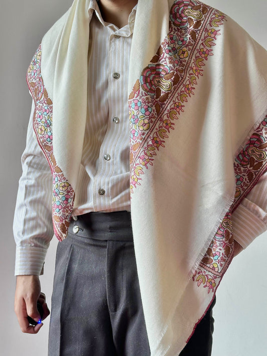 Person wearing a white shirt and patterned shawl with a neutral background